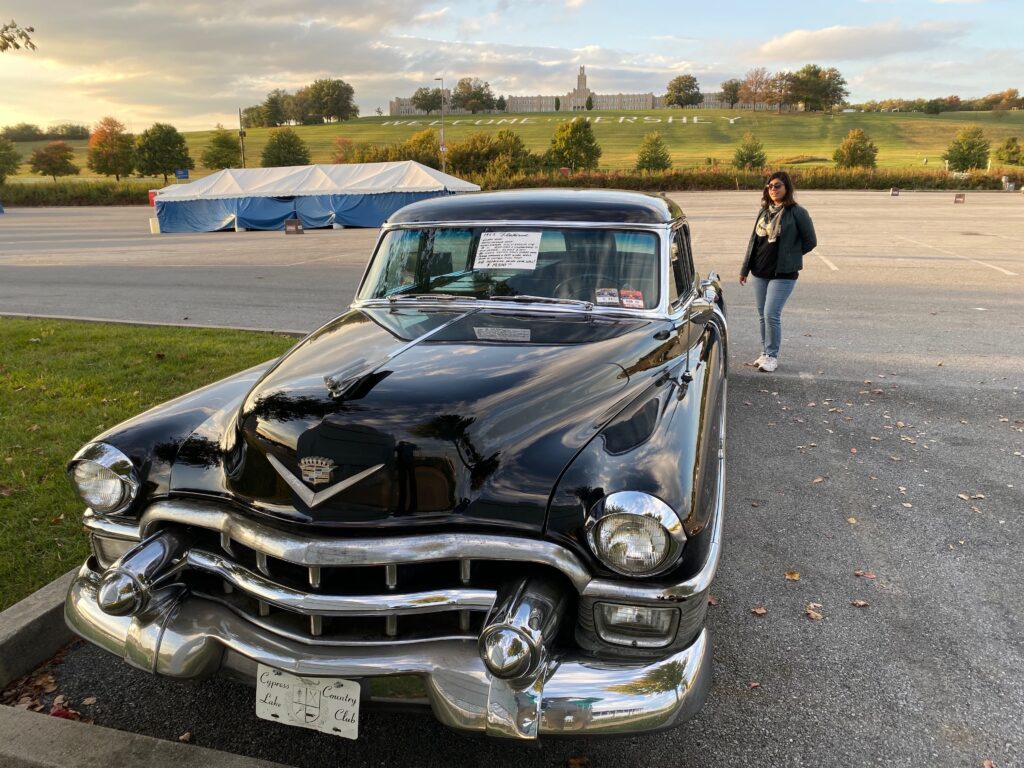 Front view of a 1953 Cadillac Sixty Special Fleetwood four-door sedan finished in black. The picture was taken at the 2019 AACA Hershey swap area in Pennsylvania. In the background