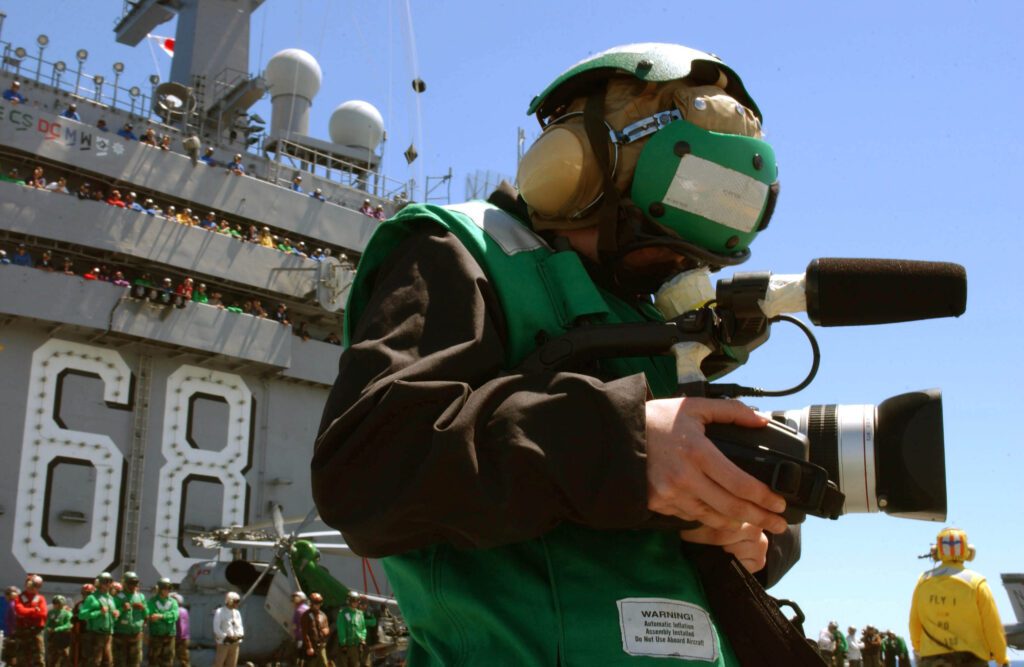 Pacific Ocean (Aug. 24, 2004) – Photographer’s Mate 3rd Class Elizabeth Thompson from San Francisco, Calif., documents flight operations on the flight deck for a video production a